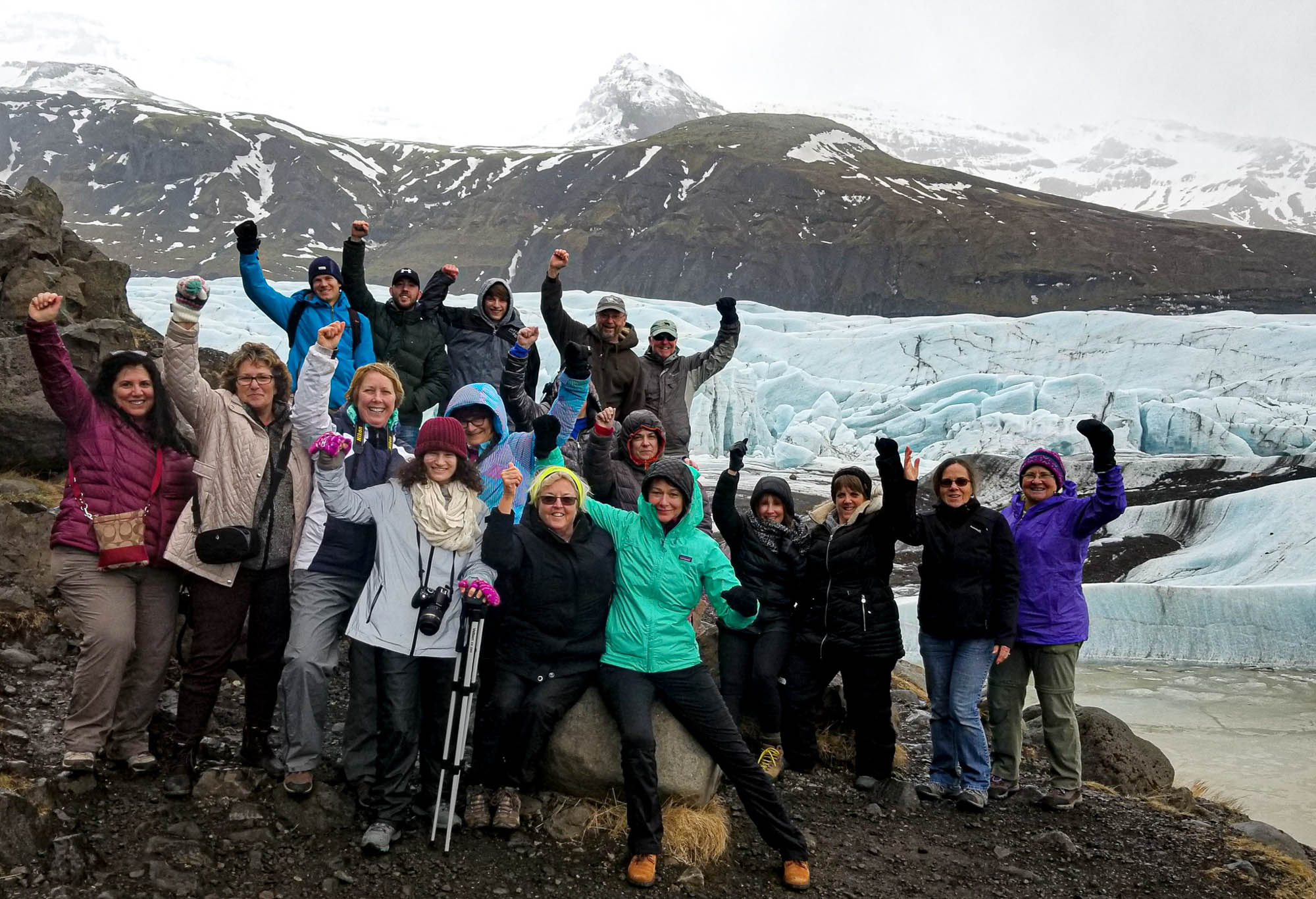 Tour group standing by a glacier in iceland cheering