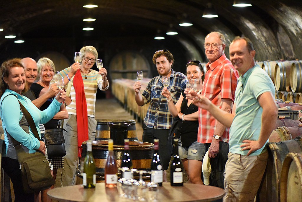 People standing in wine cellar tasting wine